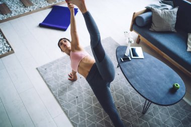 Eşofmanlı, beyaz, formda bir kız modern apartman dairesinde egzersiz yapmaktan zevk alıyor. İnzivaya çekilme eğitiminde Hatha asana 'yı motive eden dişi yogiler mükemmel vücut şekli ve zayıf vücut yapısını koruyorlar.