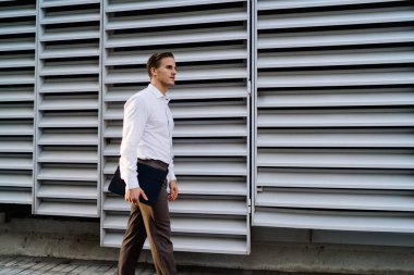 Şehir merkezinde şehir arka planında dijital tabletle gezen akıllı sıradan girişimcilerin yan görüntüsü, modaya uygun giyinmiş Kafkasyalı iş adamı elinde modern ellerle metropolitan caddesinde