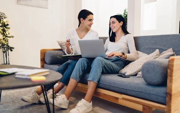 Positive Women Casual Clothes Notebook Laptop Having Conversation Sitting Sofa — стоковое фото