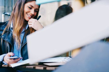 Genç bir bayanın altında dişlek gülüşlü bir şekilde harita ve akıllı telefon eşliğinde caddede oturuyor.
