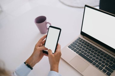 Resmî giysiler içinde yüzsüz serbest çalışan boş ekranlı akıllı telefona göz atan ve gün ışığında bilgisayarı kullanan biri.