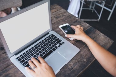 Yazlık kafedeki yıpranmış ahşap masaya cep telefonu koyan anonim kadının yüksek açılı görüntüsü Netbook projesine hazırlanırken
