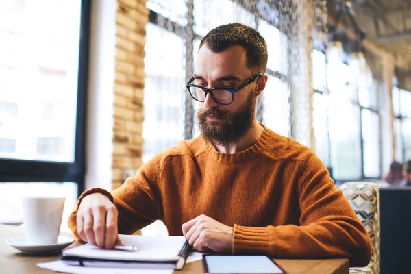 Seriös Fokuserad Skäggig Kille Casual Outfit Och Glasögon Tittar Anteckningar — Stockfoto