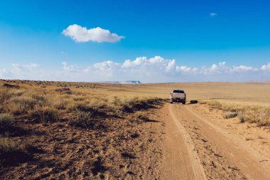 Torysh Toplar Vadisi 'nde boş kumlu yolda tek başına araba sürerken yaz tatilinde havanın güzel olduğu bir günde yolculuk yapmak.