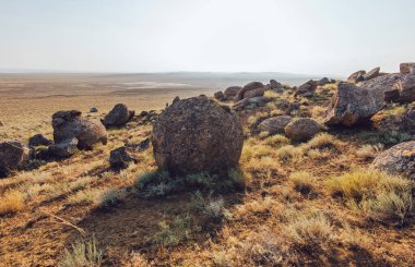 Büyük kaya manzarası Torysh Balo Vadisi 'nde gündüz vakti bulutsuz gökyüzünün altında kurumuş bitki örtüsüyle tepede taşlarla çevriliydi.