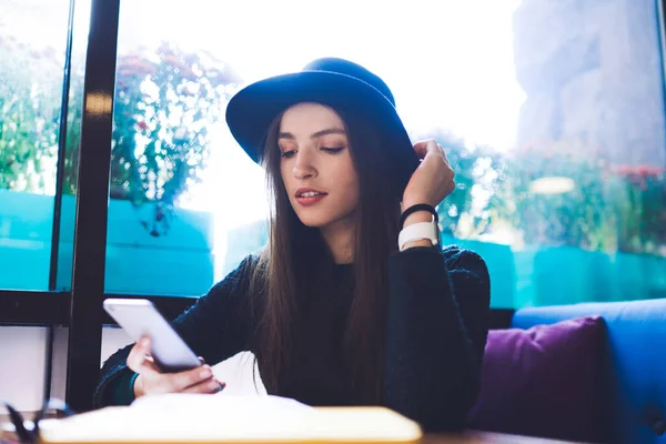 Serious Female Casual Black Outfit Hat Sitting Table Window Using — Fotografia de Stock