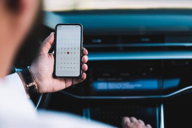 Takvim uygulamasındaki programa bakmak için dokunmatik ekranlı modern taşınabilir cep telefonu kullanan tanımlanamayan erkeğin arka planı