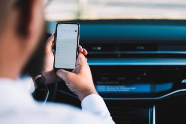 Otomatik otururken modern kablosuz cep telefonu uygulaması kullanan, kol saati olan tanınmayan bir adamın arka planı