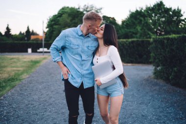 Kafkas kadın metin yazarı, dijital netbook ile erkek arkadaşını öpüyor kot gömlekli, şehirde yürüyüş randevusunun keyfini çıkarıyor, güzel görünümlü, bilgisayarlı blogcular bilgisayarla sarılıyor.