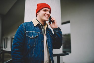 Yakışıklı, sıradan giyinmiş, sokakta boş vakit geçirirken cep telefonuyla konuşan erkeklerden.