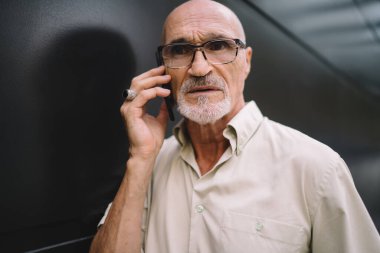 Optik gözlüklü ciddi bir üst düzey erkeğin göz düzeltmesi için yakın plan çekimleri. Uluslararası akıllı telefon sohbetini klasik gözlüklü beyaz adamın danışmanlık çağrısı yapmasına neden oluyor.