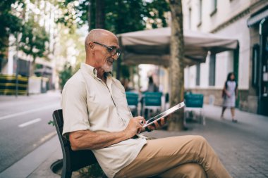 Olgun blog yazarı çevrimiçi modda sohbet ve mesajlaşma için 4G 'ye bağlanıyor, klasik gözlüklerde son sınıf öğrencisi şehir bankında ve ağ kurmada dinlenen modern dokunmatik bloglarda e-posta aldı