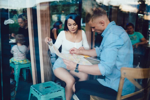 Través Vaso Diversa Pareja Enfocada Sentada Mesa Madera Cafetería Moderna —  Fotos de Stock