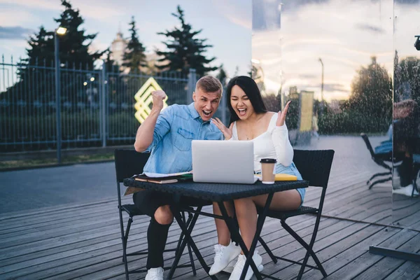 Cheerful Young Couple Casual Clothes Sitting Table Laptop Cup Coffee — Fotografia de Stock