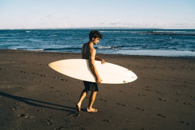 Sportif erkek gezgin Sri Lanka 'da deniz sörfü yaptığı için tatil yapıyor. Kafkasyalı kaygısız bir adam okyanus dalgalarında eğlenmeye hazır.