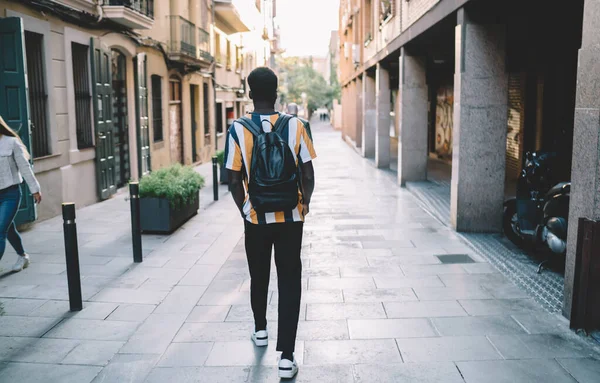 大学に行く革のバックパックを持つトレンディーな服装の男性学生のビュー カジュアルな服でスタイリッシュなアフリカ系アメリカ人観光客新しい町を訪問するために休暇を過ごす旅行都市を歩く — ストック写真