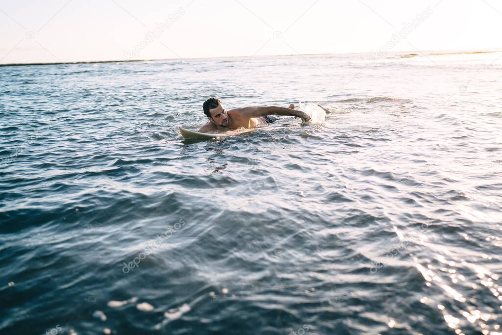 Surfer floating in ocean waiting for large wave during touristic vacation to Malibu California, Caucasian guy swimming in sea enjoying sportive activity during getaway travel to Philippines