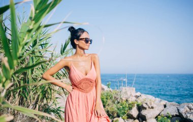 Güneş gözlüklü, plaj kıyısında durup uluslararası tatilleri düşünen Filipinler 'deki okyanus ortamını keşfeden Latin bir kız.