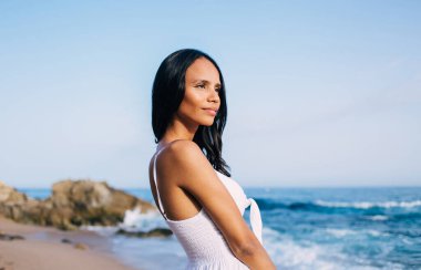 Sakin sahil sahillerinde sakinlik hisseden, yolculuk boyunca gezinti yapan, düşünceli bir kadın tropikal sahil şeridinde hayat tarzını düşünmek için zaman harcıyor.