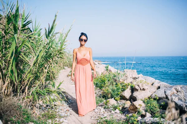 Sahilde yürüyen ve kameraya gülümseyen neşeli Latin turistin tam boy portresi güneş gözlüklü neşeli kadın gezgin seyahat sırasında Filipinleri keşfediyor.