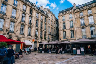 Bordeaux şehir merkezinde büyük rendelenmiş camları olan antik anıtsal binaların yakınında açık kafeler ve sokak satıcıları olan merkez meydanı.