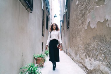 Kendine güvenen, esmer, modaya uygun kıyafetli, dar caddelerde yürüyen, güzel, Afro-Amerikan kadını şık giyinmiş, şehir ortamlarında gezinen...