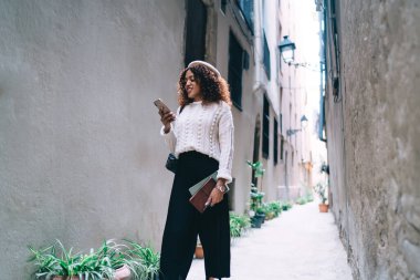 Dalgın koyu tenli, milenyum yeniyetme kız akıllı telefondan internet sitesine girip videolar izliyor. Güzel Afro-Amerikan kadın gezgin boş zamanlarında şehir sokaklarını keşfetmek için navigasyon uygulaması kullanıyor.