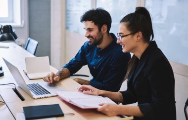 Dost canlısı, çok ırklı, resmi giyinen, dizüstü bilgisayarda çalışan, modern ofiste dizüstü bilgisayarlı genç profesyoneller.