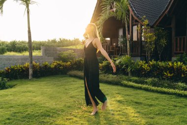 Arkadaki sıska kadın vücudu yeşil bahçede serinliyor ve kırsalda vakit geçirirken güneşli bir yaz gününün tadını çıkarıyor.