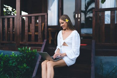 Dizüstü bilgisayarda yeni bir başlangıç stratejisi üzerinde çalışırken verandada oturan meşgul kadın girişimcinin yan görünümü