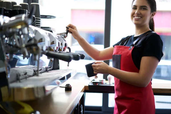 陽気なブルネットの女性の肖像バリスタは マシン上でアロマ飲料注文を準備するエプロンでプロのイタリック機器 笑顔の女性従業員で働くコーヒーハウスでの仕事に満足 — ストック写真
