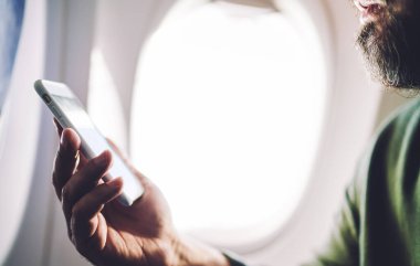 Yüzü sakallı, sakallı, cam kenarında oturan ve yaz aylarında akıllı telefonlara bakan...