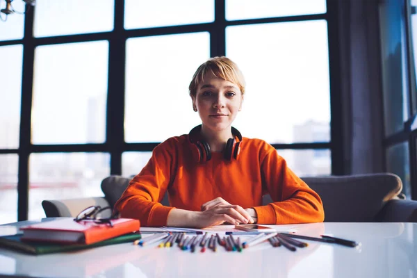 Joven Diseñadora Sonriente Con Auriculares Sentados Mesa Con Libros Papel —  Fotos de Stock