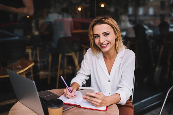 Cheerful Woman Freelancer Using Smartphone Taking Notes While Working Project — Stockfoto