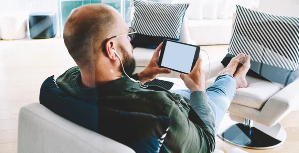 Bakvendt Bilde Mann Med Øretelefoner Som Slapper Myk Lenestol Mens – stockfoto