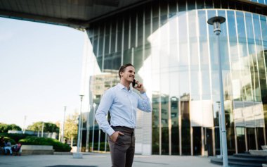 Başarılı iş adamı, şehir merkezindeki iş molasında uluslararası sohbetten keyif alıyor, 4G internete bağlanan mutlu beyaz erkek şehir ortamında arama ve konuşma için dolaşıyor.