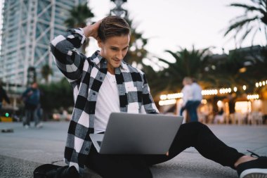 Bin yıllık erkek öğrenci e-postaları kontrol ediyor ve sokaktaki dizüstü bilgisayarını kullanarak web sayfasından bilgi okuyor. Yetenekli dijital göçebe video izliyor ve uzak iş hakkında bilgi topluyor.