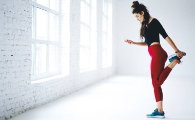 Sosyal ağlarda çevrimiçi blog yazarken bacaklarını esneten aktif sporcu kadın, akıllı telefon aygıtı ile SMS gönderirken egzersiz sırasında genç fitness kız mesajlaşması ve mesajlaşması