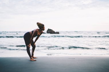 Eşofmanlı esmer tenli koşucu, kardiyo yapmak için deniz kıyılarında koşar. Sahil şeridindeki boş zamanlarında vücudu rahat olan çekici bir zenci kadın.