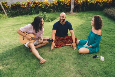 Yüksek açılı mutlu çeşitli arkadaşlar gündelik kıyafetlerini giyer, güler ve gitar eşliğinde eğlenirler.