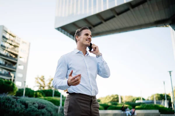在金融区 一位穿着白衬衫的英俊商人因与他人进行智能手机咨询服务对话而与他人联系在一起 他自信地通过手机应用程序给一位男性创业者打电话 — 图库照片