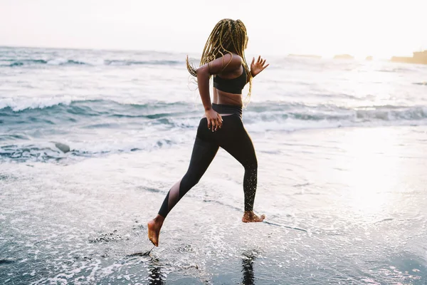 非洲裔美国妇女跑步者 身材随意 每天早上都在海边跑步 身穿运动服的年轻女运动员沿着海滩慢跑 与大海保持健康的生活方式和积极的身体联系 — 图库照片
