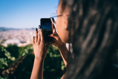 Kaçış sırasında fotoğraf çekmek için akıllı telefon kamerası kullanan tanınmayan bir kadının arka planı. Koyu tenli kadın blogcu cep telefonu uygulaması ile mobil video blogu çekiyor.
