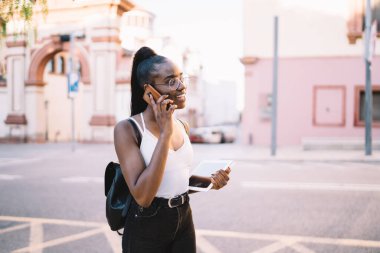 Koyu tenli neşeli hippi turist, elinde temasla arkadaşını arıyor. Gezici gezintiler hakkında konuşuyor. Optik gözlüklü mutlu siyah kadın uluslararası hücre sohbetinin tadını çıkarıyor.