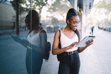 Mutlu hipster kızı, internet ve internet iletişimi için 4G kablosuz bağlantısını kullanırken seviniyor. Klasik gösterilerde neşeli kadın turist blogları turizm ve gezi hakkında yayın yapıyor.