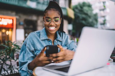 Mobil cihazlı mutlu bir kadın elinde komik videolar izliyor ve gülümsüyor, esmer tenli serbest yazar bilgisayar kullanarak kanal haberleri ve yayınları okumaktan zevk alıyor.