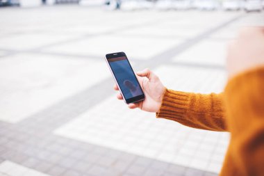Cep telefonu kullanan, arkadaşlarıyla iletişim kuran ve sosyal ağları kontrol eden isimsiz bir kişi şehrin caddesinde boş zamanlarında duruyor.