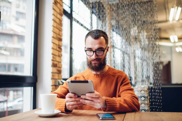 Positivo Macho Sem Barba Sentado Mesa Com Smartphone Xícara Café — Fotografia de Stock