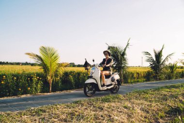 Gülümseyen bayan turist Filipinler 'de seyahat ederken doğal yollardan gidiliyor. Neşeli hippi kız yaz tatillerinde klasik scooter kullanıyor.