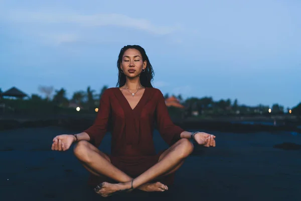 早朝に蓮のヨガポーズを練習しながら砂浜に座って瞑想しながら目を閉じてスリムアジアの女性 — ストック写真